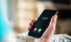 Dłoń trzyma smartfon z ekranem pokazującym "Unknown" i przyciski odbierania/odrzucania. Zastanawiasz się, kto dzwonił, numer jest nieznany.