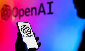Dłoń trzyma smartfon z logo ChatGPT. W tle logo OpenAI, symbolizujące rozwój gpt sztuczna inteligencja.