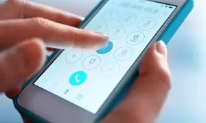 Dłoń wybiera numer na ekranie smartfona. Sprawdź numer telefonu, zanim zadzwonisz.