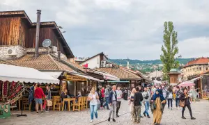 Tętniący życiem bazar w Bośni i Hercegowinie, z ludźmi spacerującymi między kramami i kawiarniami.