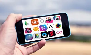 Ręka trzyma telefon z ikonami aplikacji do robienia zdjęć i edycji.