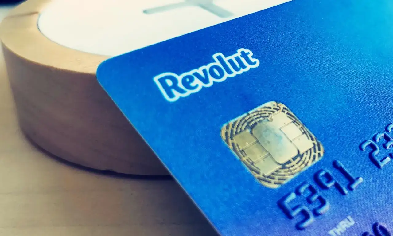 Niebieska karta Revolut z chipem, obok drewnianego elementu. Dowiedz się, jak działa Revolut, by łatwo zarządzać finansami.