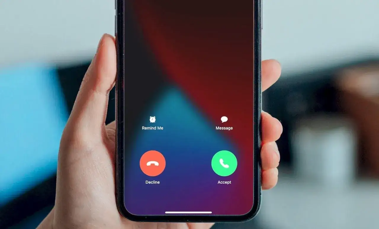 Dłoń trzyma smartfon z ekranem połączenia. Możesz odbierać połączenia bez przesuwania, wybierając 