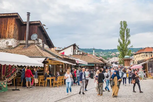 Tętniący życiem bazar w Bośni i Hercegowinie, z ludźmi spacerującymi między kramami i kawiarniami.